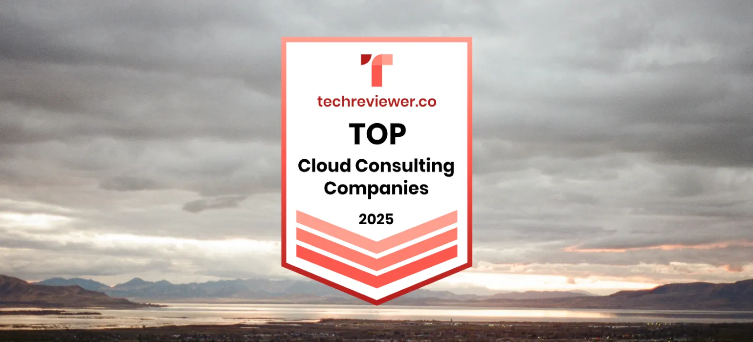 View of deep, sunset-lit clouds over a mountain valley with a large lake, which also reflects the orange sunset.